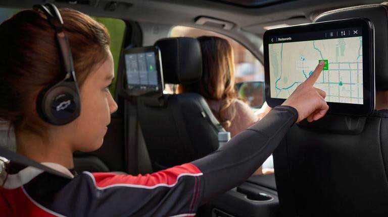2025 Chevrolet Suburban interior back seat kid with headphones on pointing at screen
