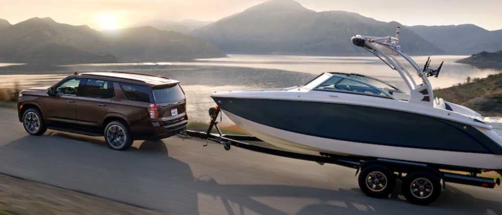 2025 Chevrolet Tahoe pulling a boat side view on road