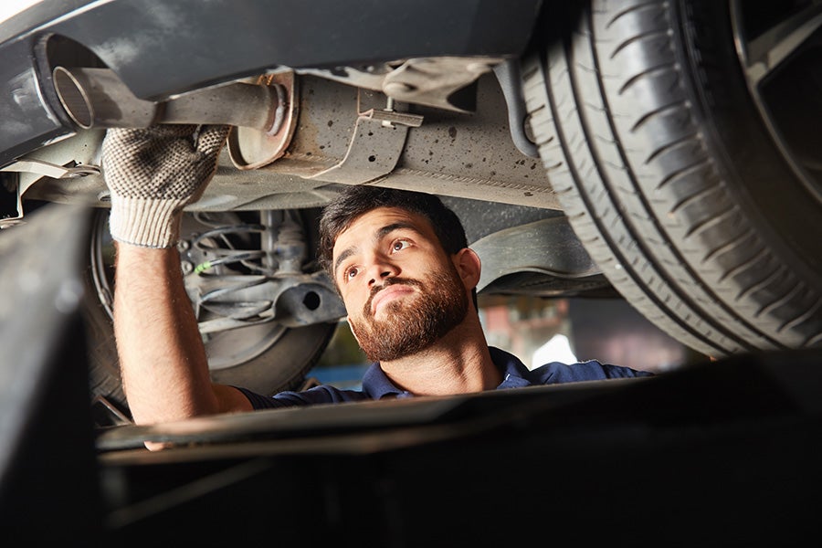 Chevrolet service technician working on muffler under car